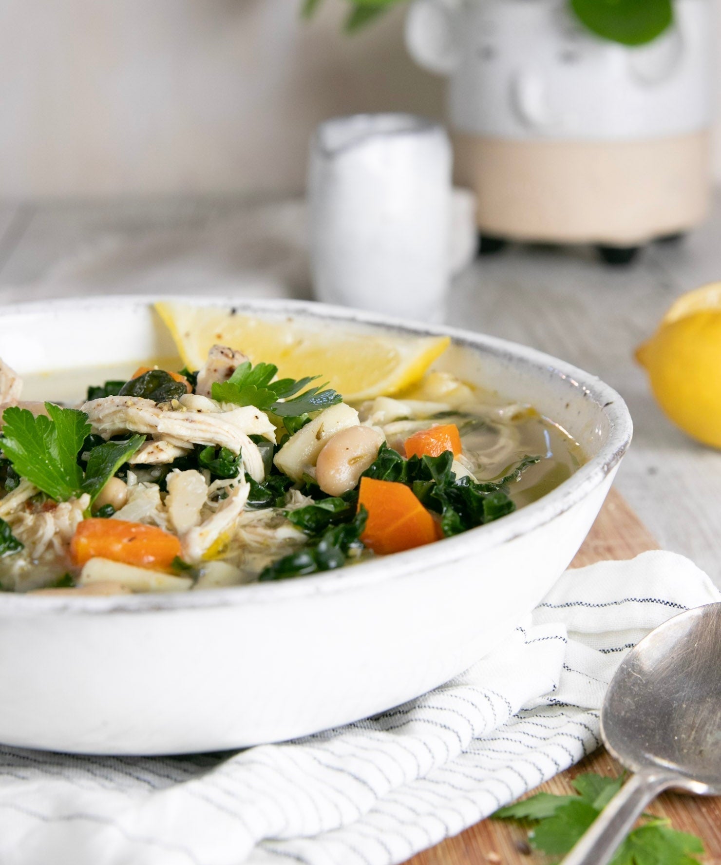Rustic Chicken Soup in a white bowl with bread and a folded napkin