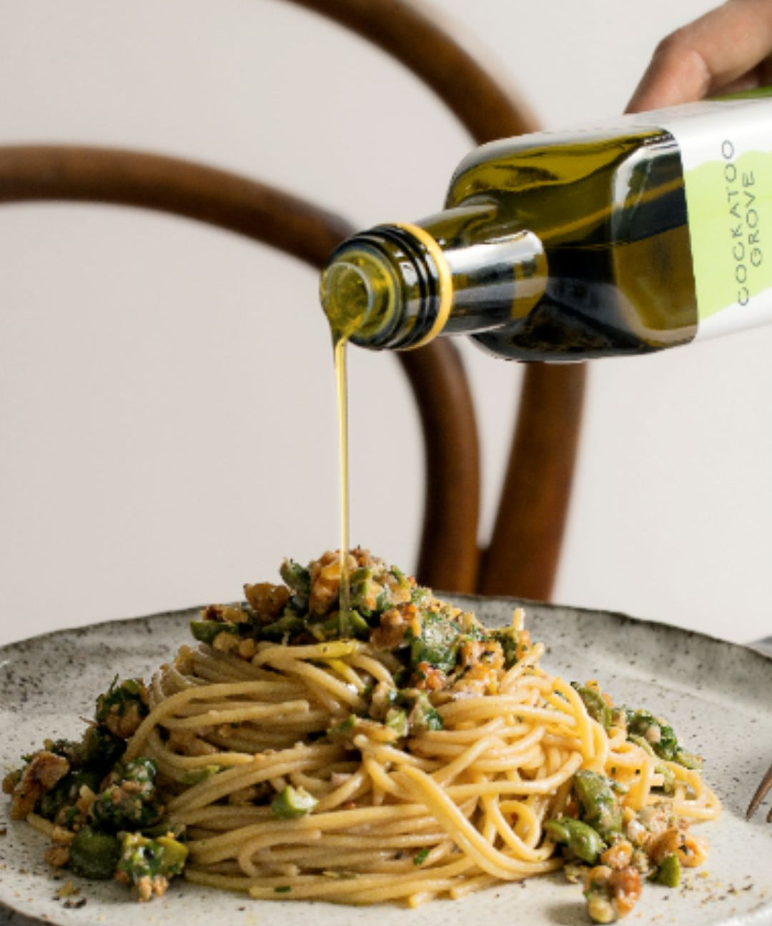pouring extra virgin olive oil onto spaghetti